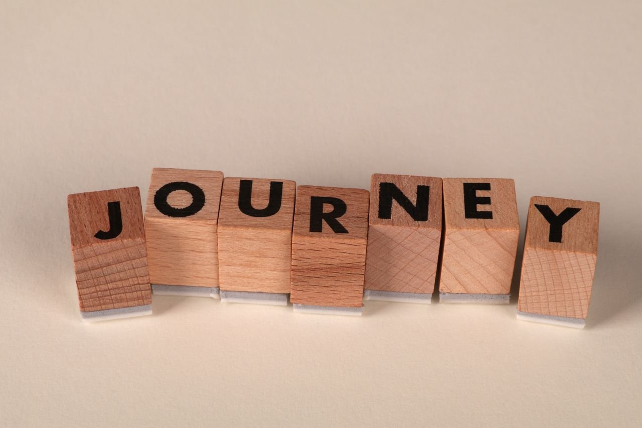 Wooden blocks arranged to spell 'Journey' on a table, symbolizing adventure or progress.