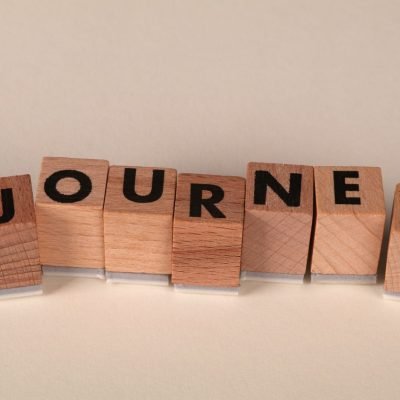 Wooden blocks arranged to spell 'Journey' on a table, symbolizing adventure or progress.